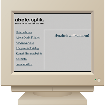 Das Bild zeigt einen alten Computer mit einer Darstellung des ersten Online-Shops von Abele Optik.